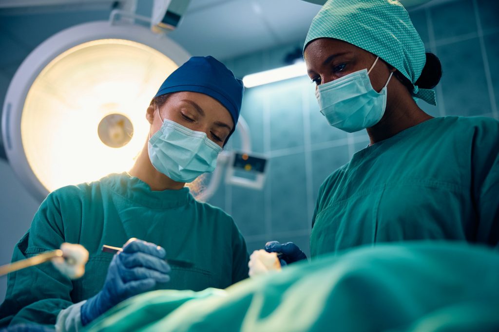 Female doctors performing surgical procedure on a patient in operating room.