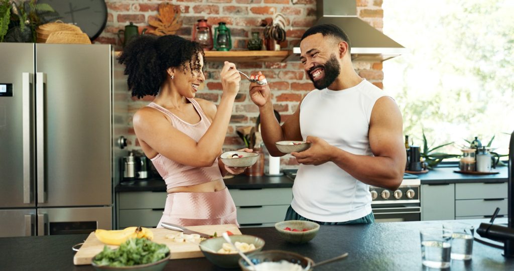 Desayuno y pareja comiendo en la cocina para una dieta saludable, nutrición y bienestar por la mañana.